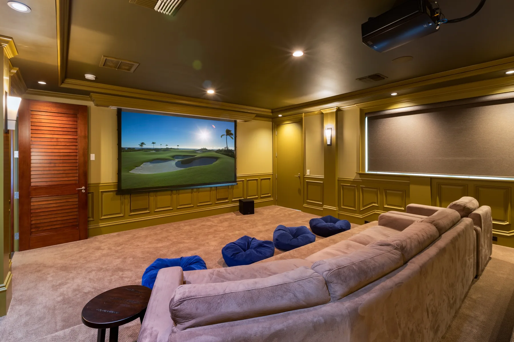 Una sala de cine en casa con asientos escalonados frente a una pantalla grande.