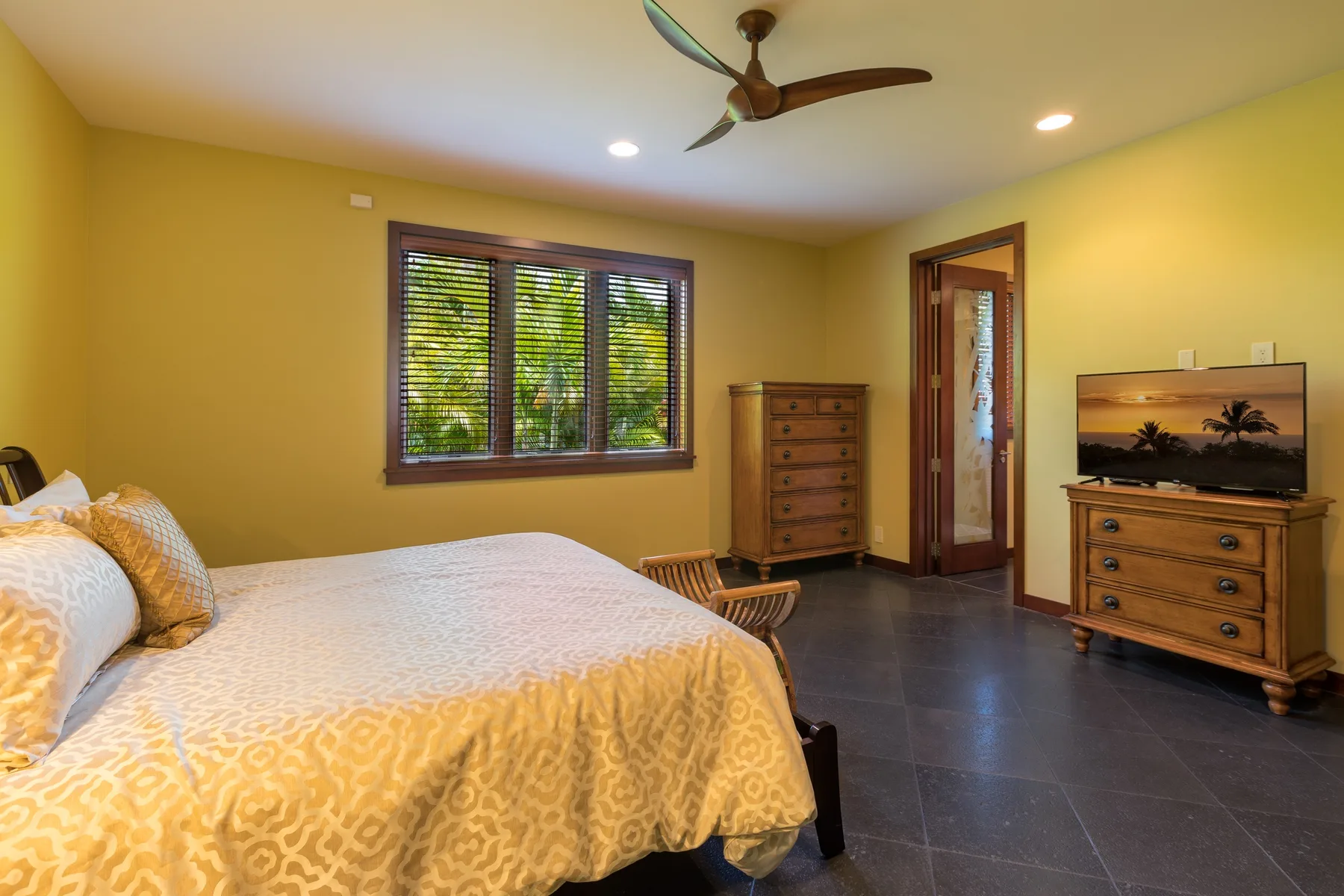 Un dormitorio con una cama grande, una ventana y cómodas de madera.