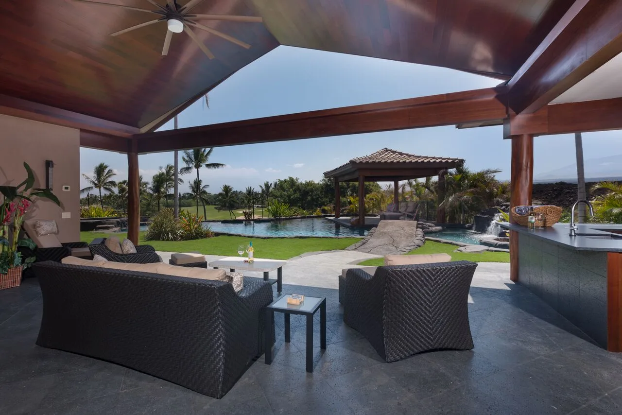 Una zona de estar exterior cubierta da a una piscina y a jardines.