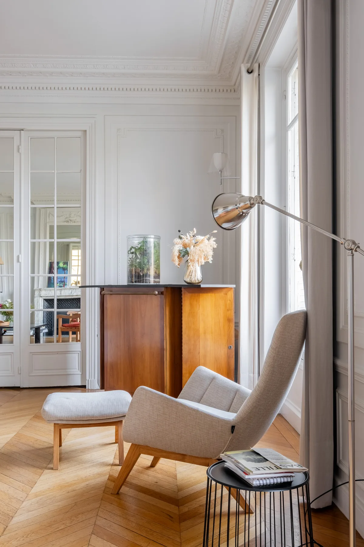 Una sala luminosa con asientos junto a un mueble de madera y ventanas altas.