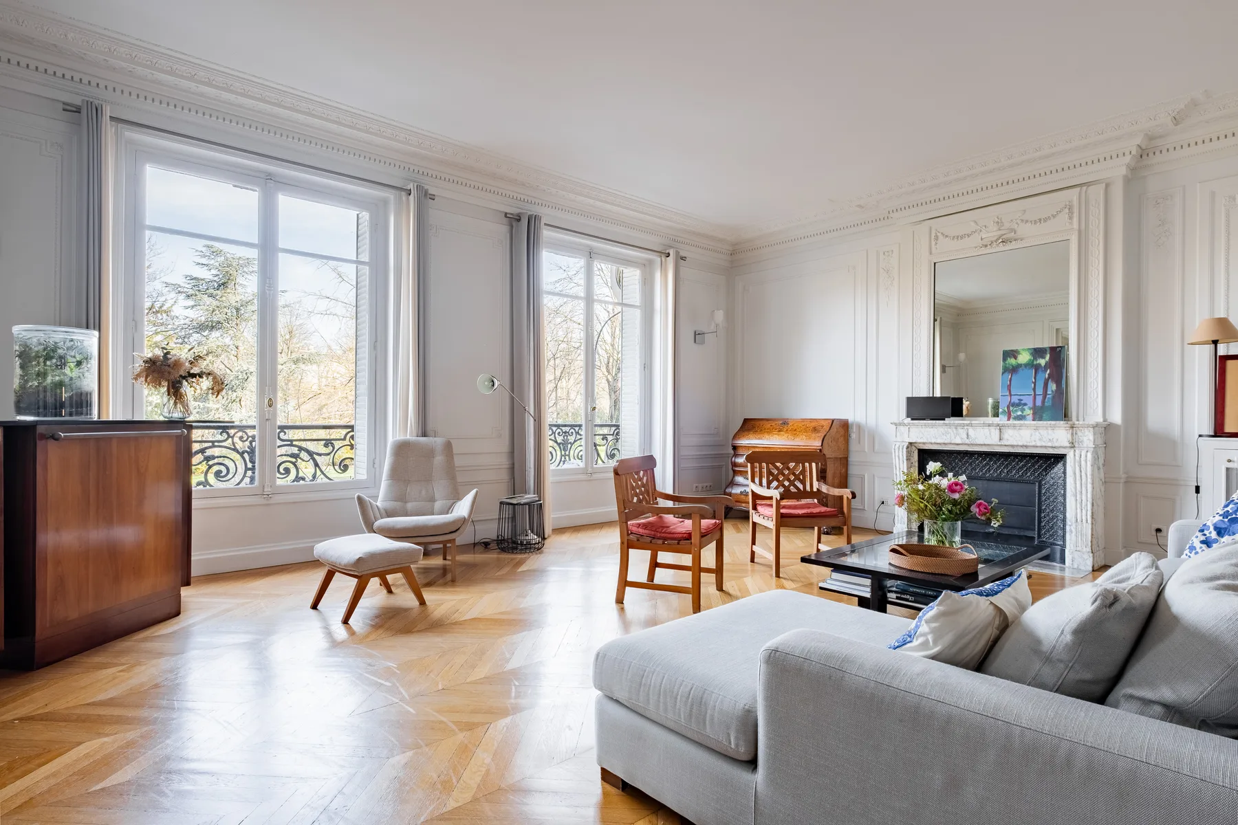A bright living room with large windows, seating, and a fireplace.