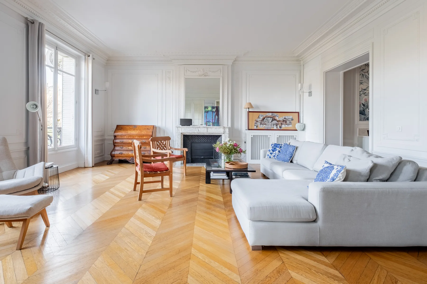 A bright living room with white seating and a wooden floor.