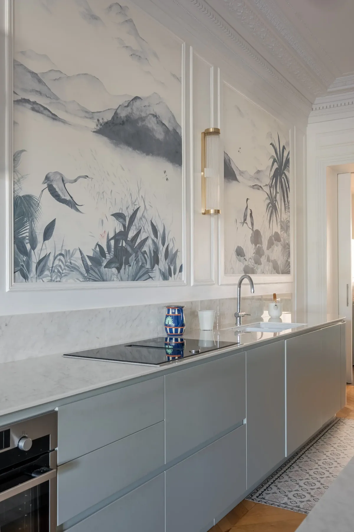 Una cocina moderna con gabinetes grises y grandes murales botánicos en la pared.