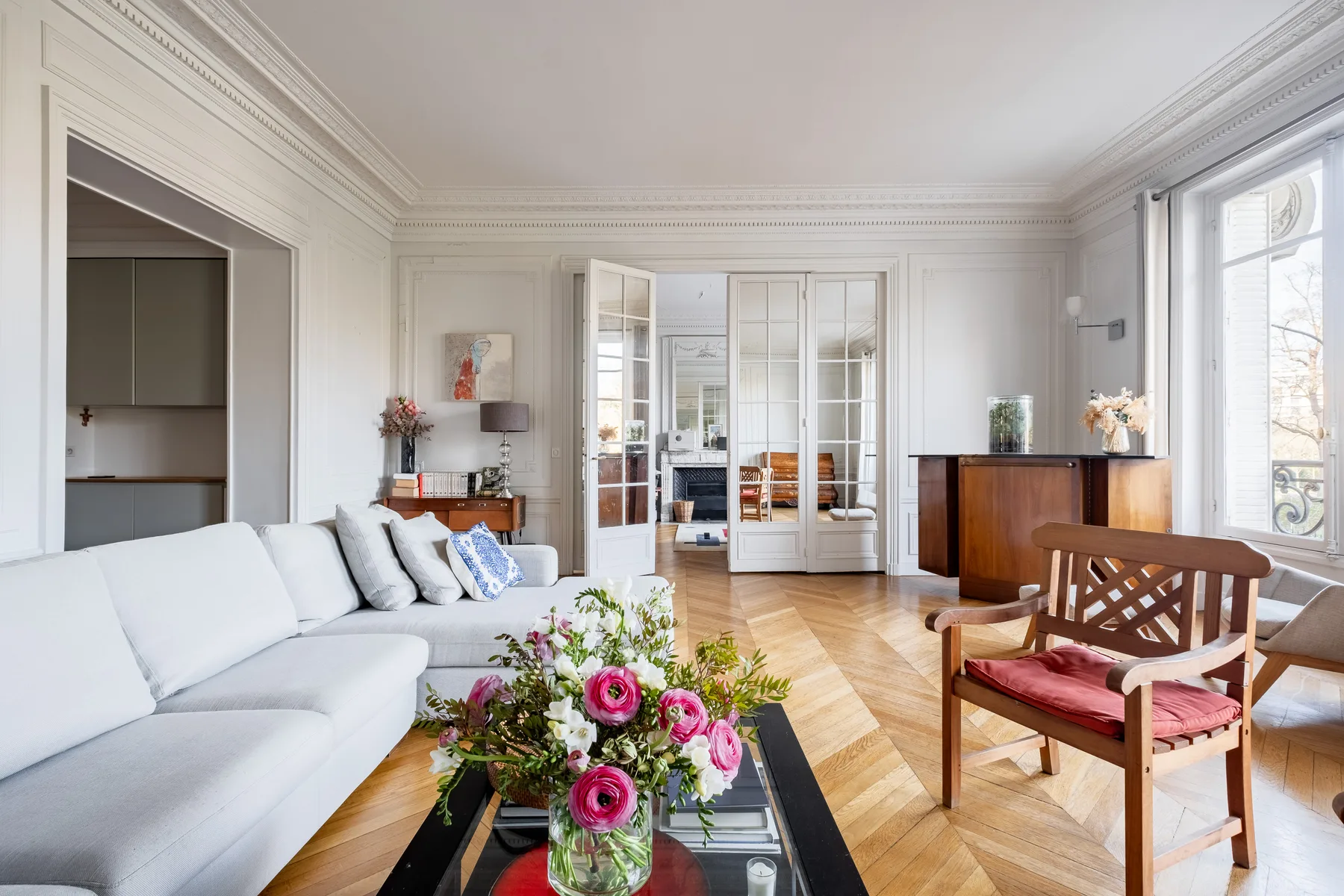 A bright living room with seating, a coffee table, and tall windows.