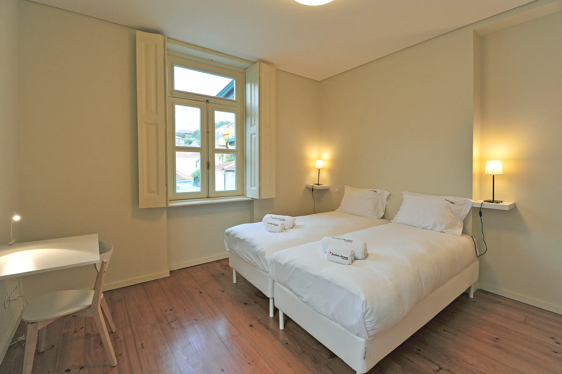 Un dormitorio con una cama doble, lámparas de noche y una ventana.