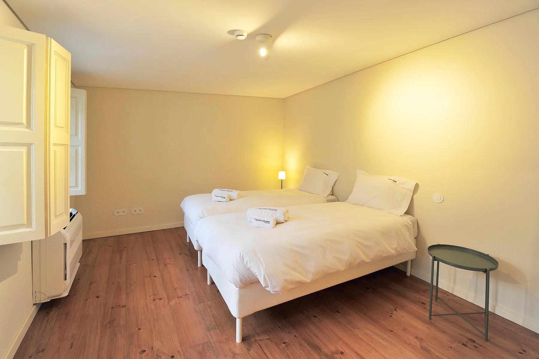 A bedroom with two beds, white bedding, and a small bedside lamp.