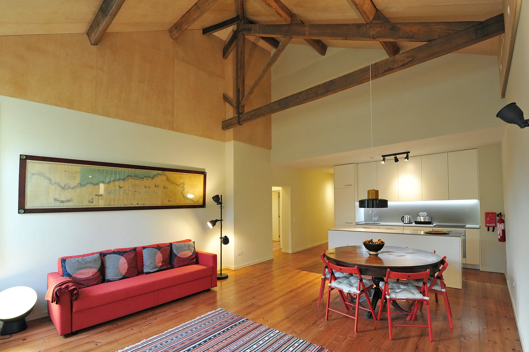 Una sala-comedor diáfana con un sofá rojo y una cocina.