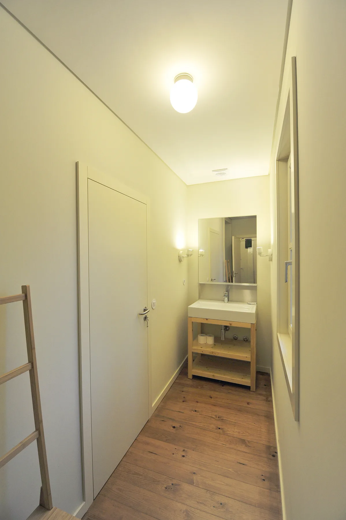 Un pasillo estrecho conduce a un lavabo con espejo.