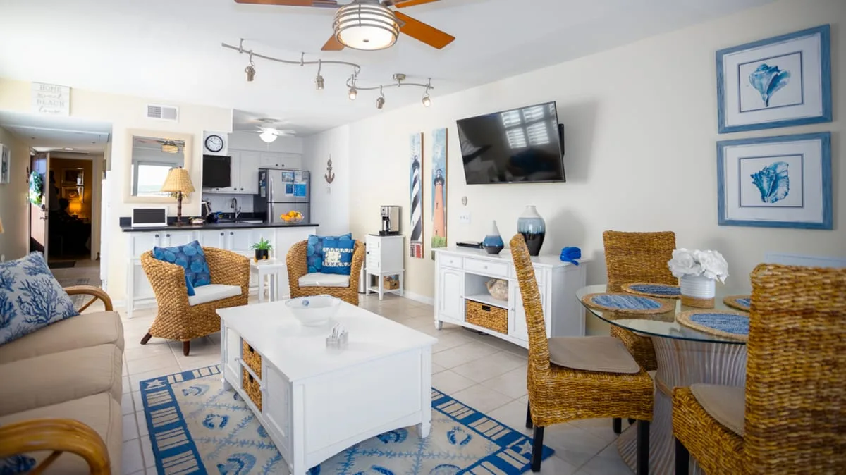 A bright open-plan living and dining area has wicker seating and a white coffee table.