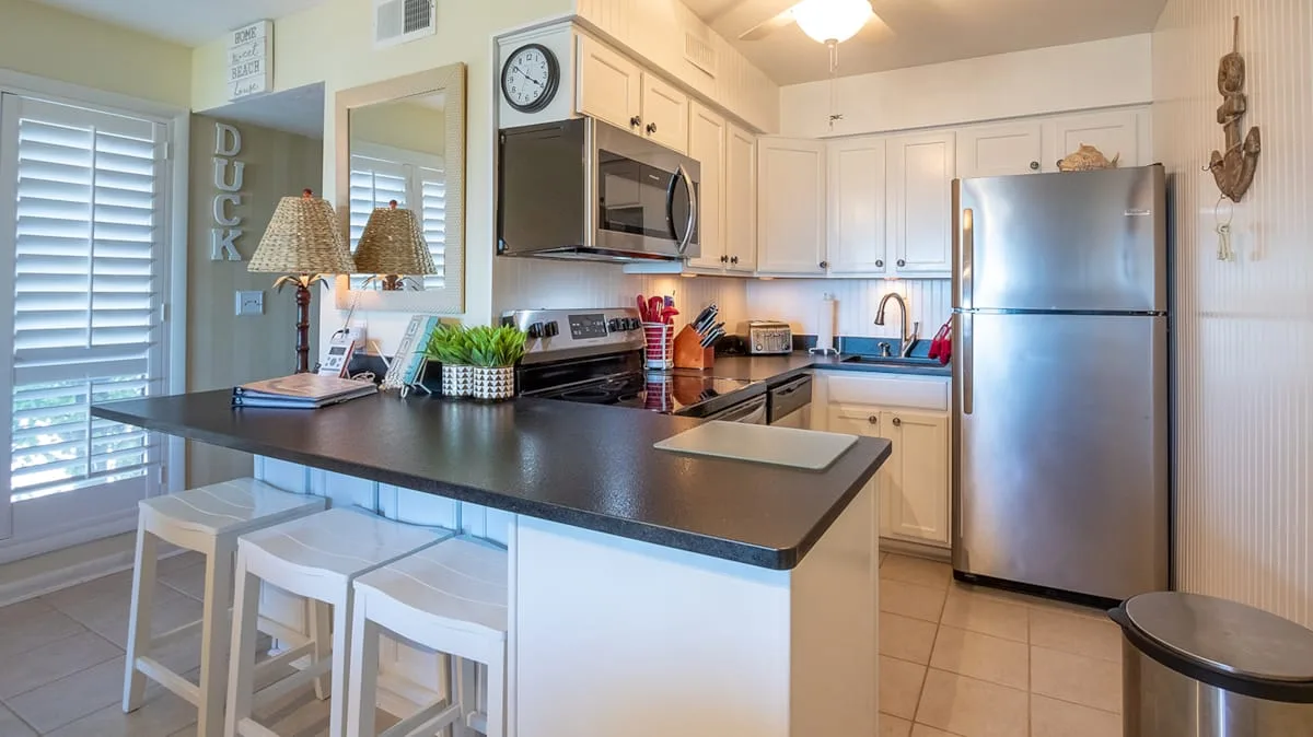 A bright kitchen with white cabinets, stainless steel appliances, and a broad island.