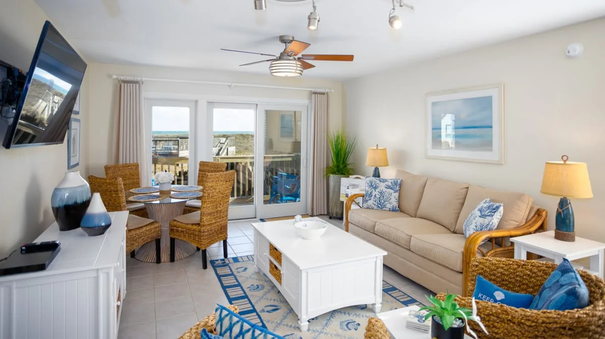 A bright living room with a seating area, coffee table, and sliding glass doors.