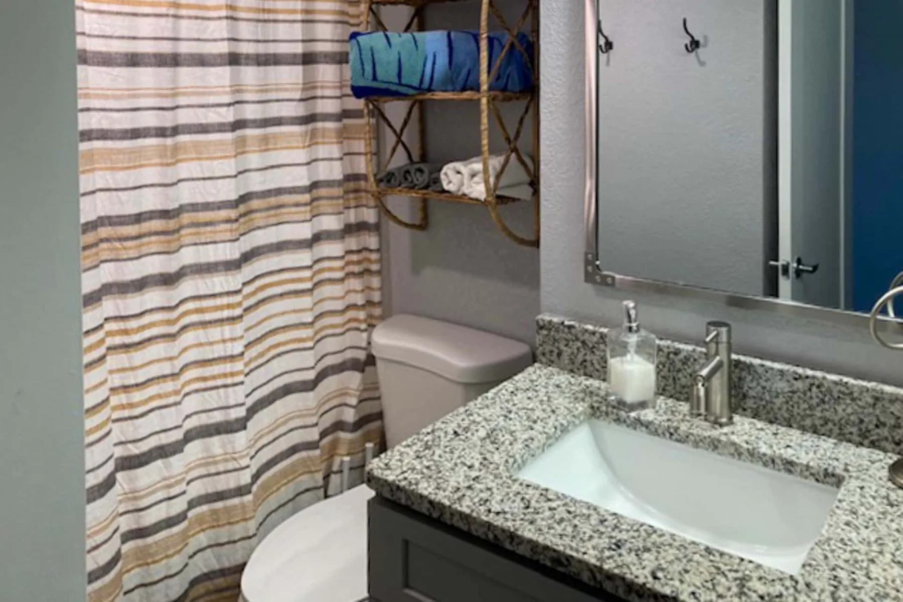 Un baño con lavabo, inodoro y cortina de ducha a rayas.