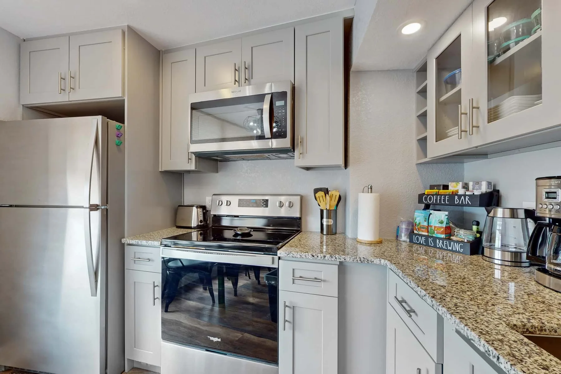 Una cocina luminosa con gabinetes blancos, electrodomésticos de acero inoxidable y encimeras de granito.