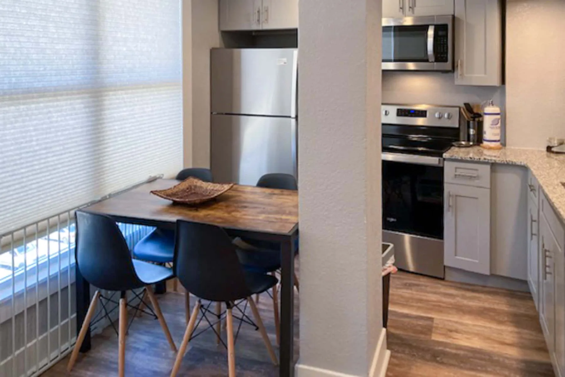 Comedor junto a una cocina compacta, con una mesa y asientos oscuros.