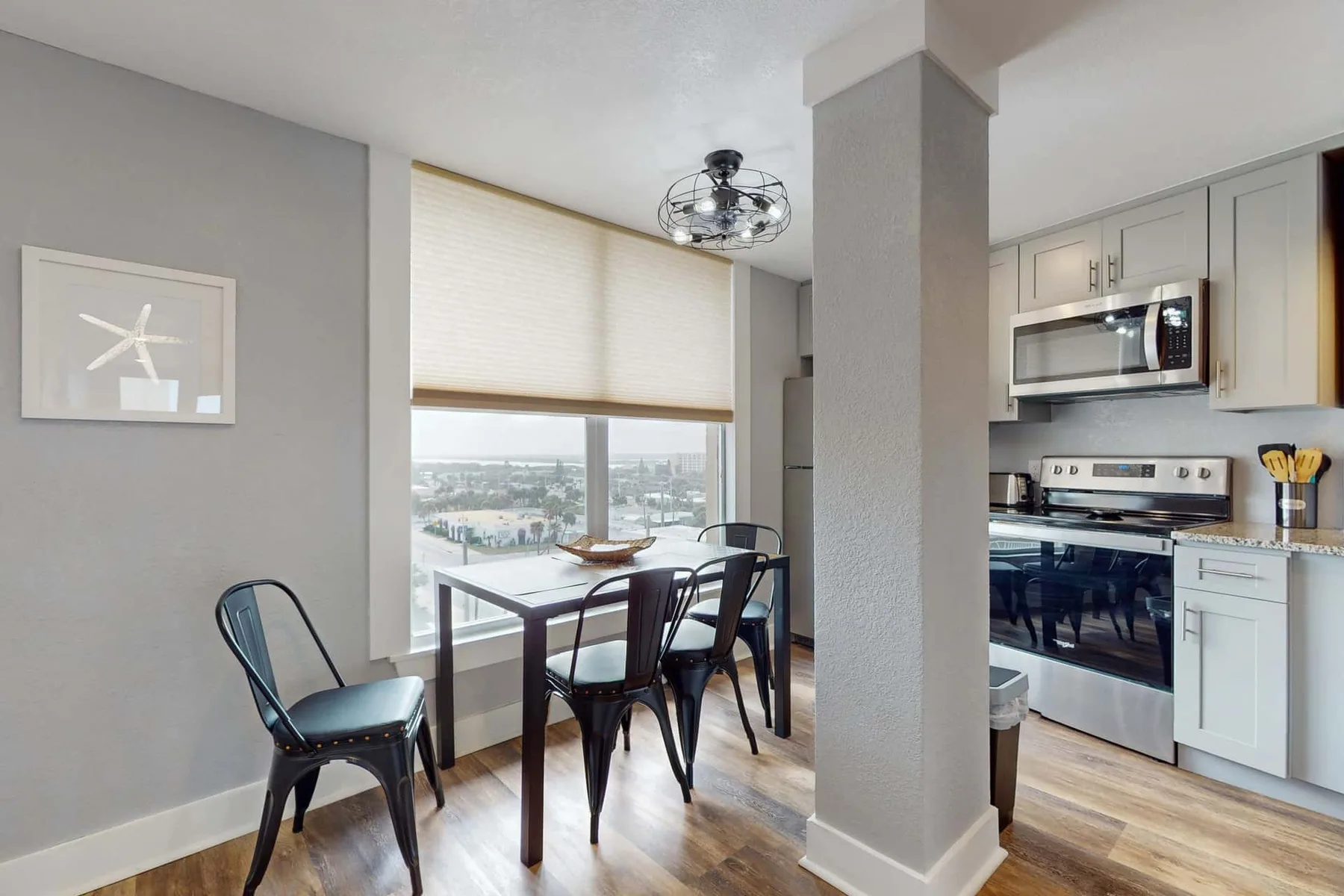 Un comedor junto a una ventana está al lado de una cocina compacta.
