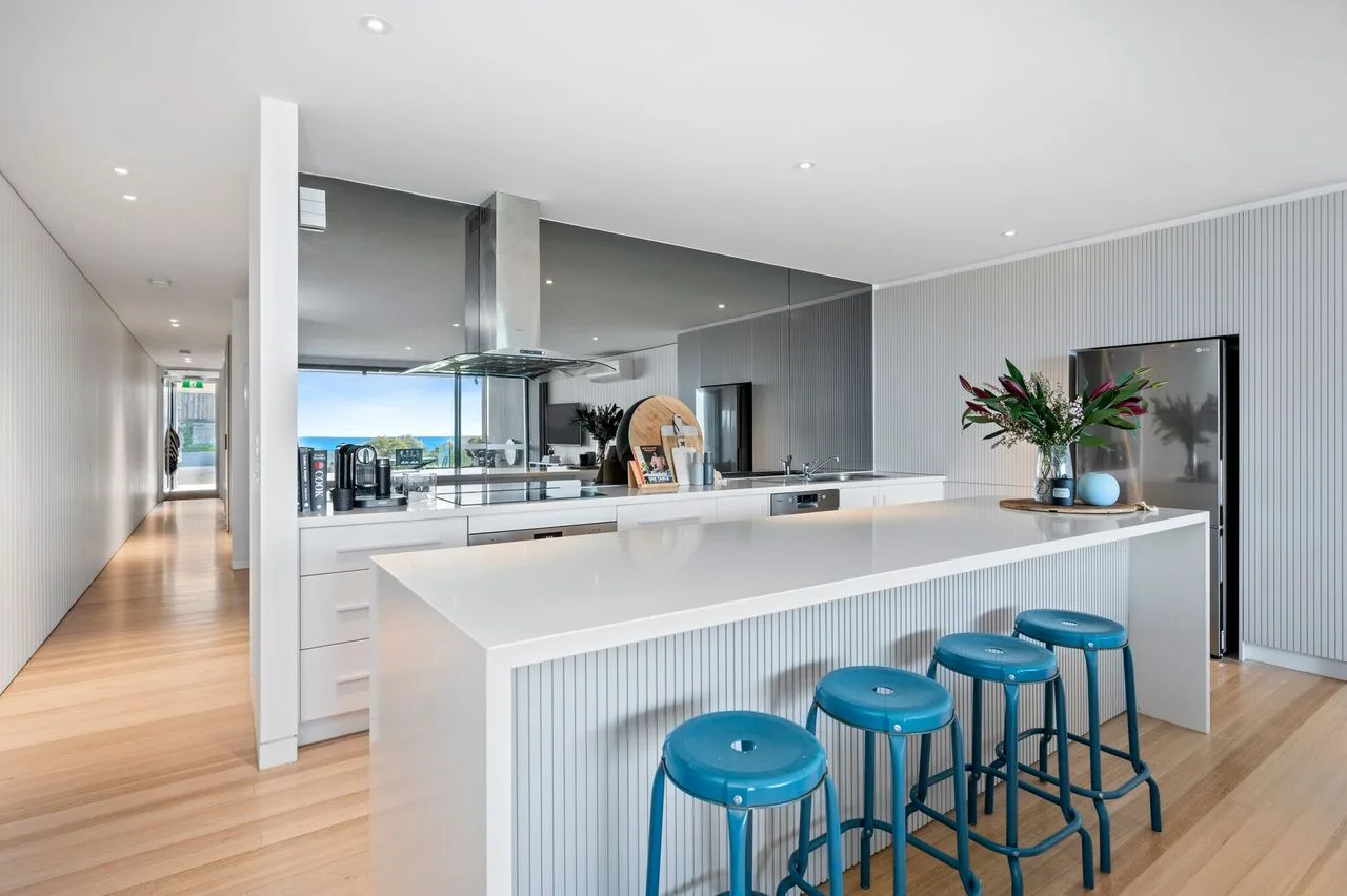 Una cocina moderna con una isla larga y taburetes azules.