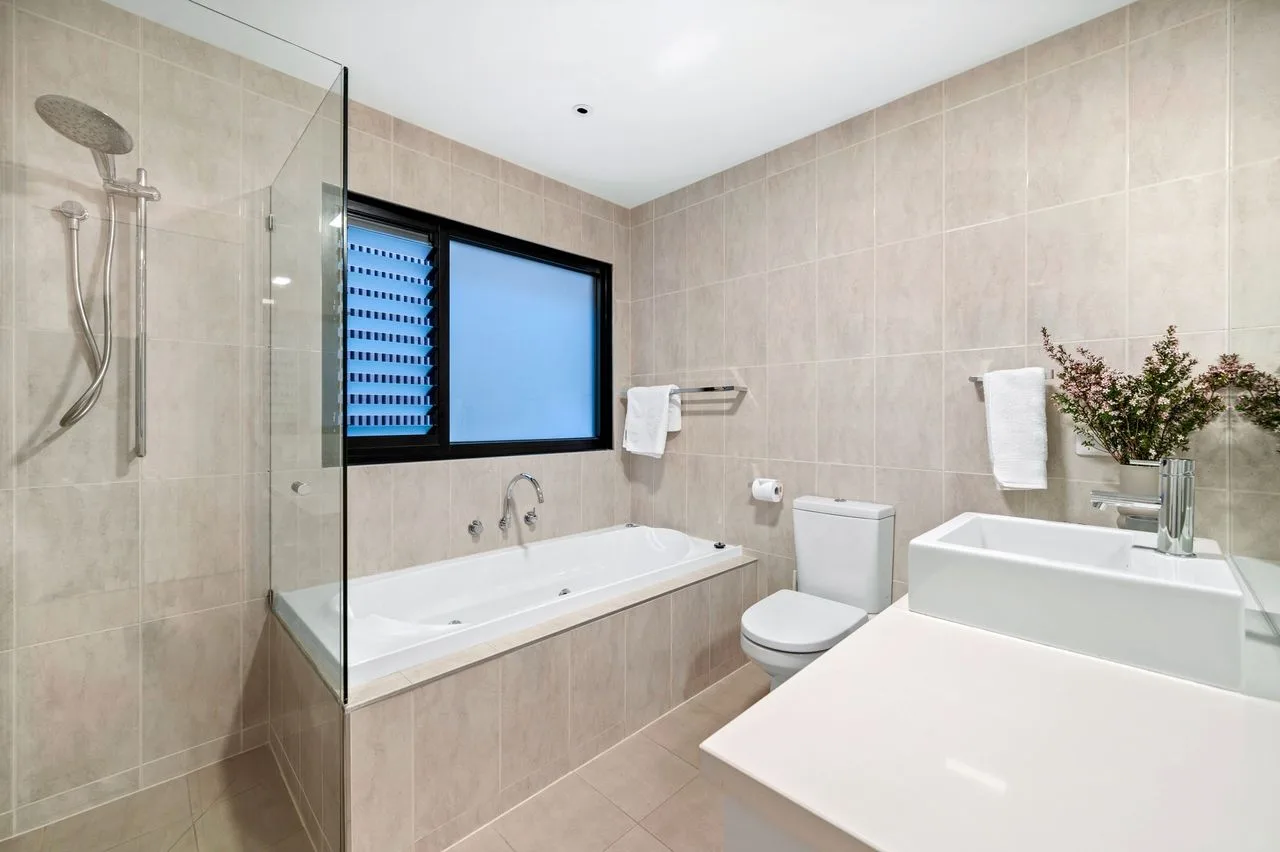 Baño con azulejos, bañera, ducha y lavabo.