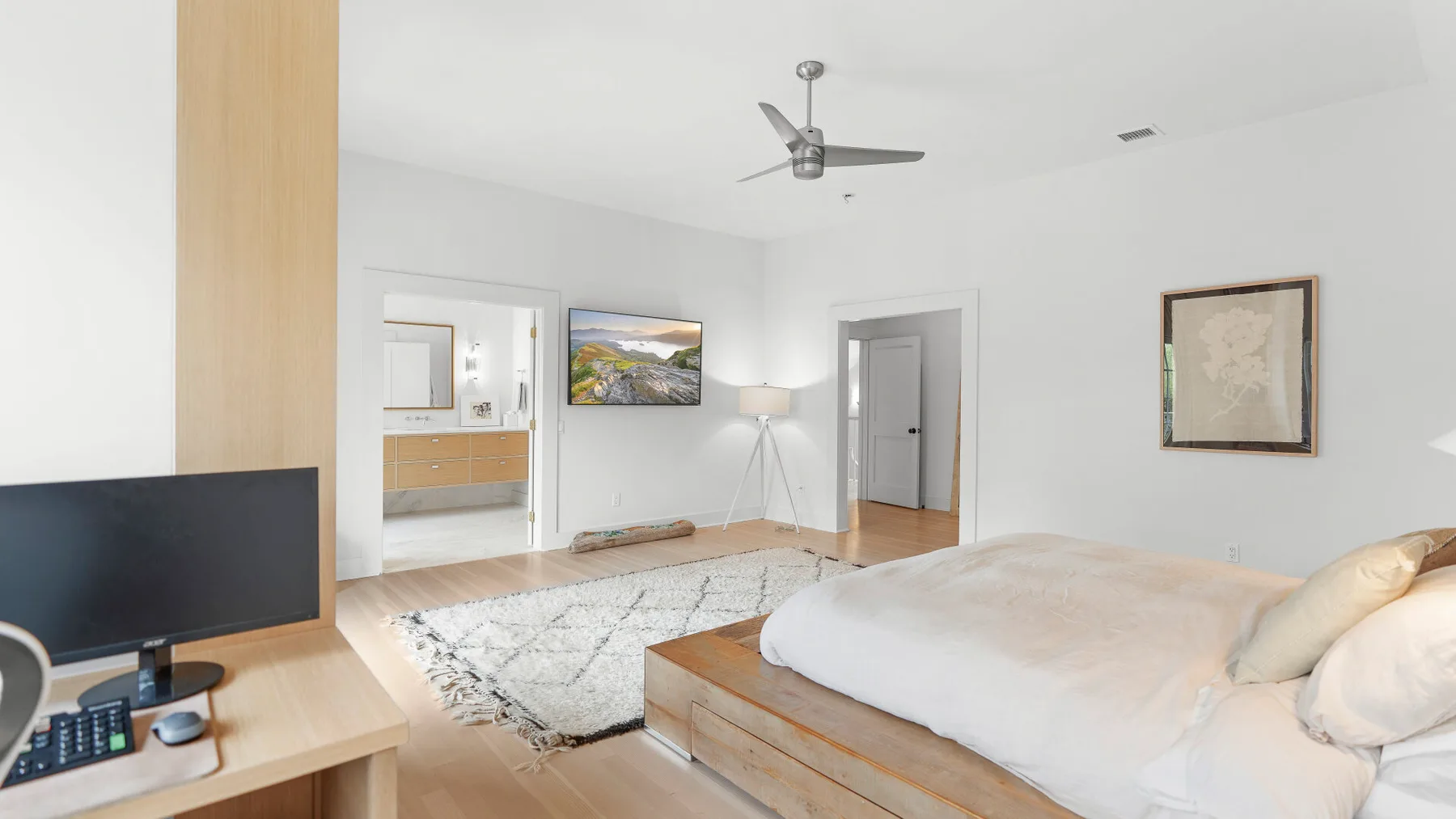 Un dormitorio luminoso con una cama grande, una alfombra y un televisor.