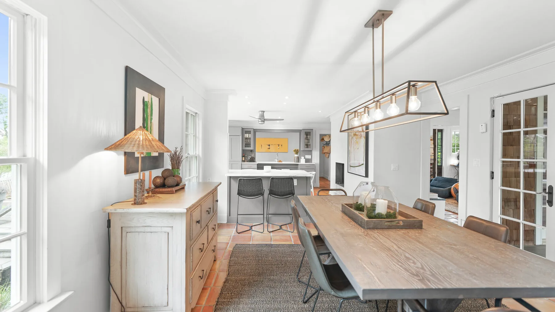 Un comedor luminoso con una mesa larga y una cocina abierta al fondo.
