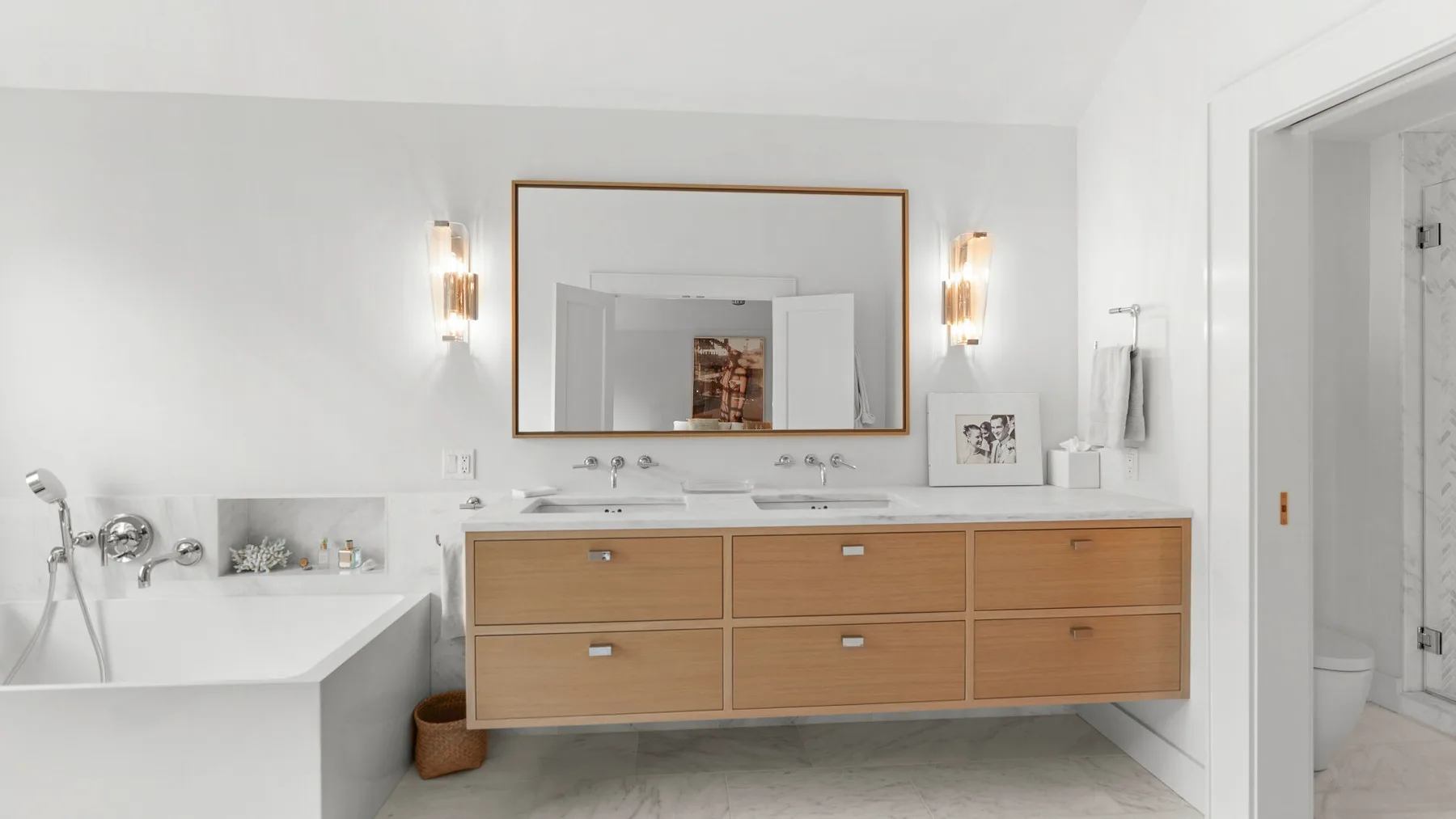 Baño con un tocador de dos lavabos, espejo y bañera.