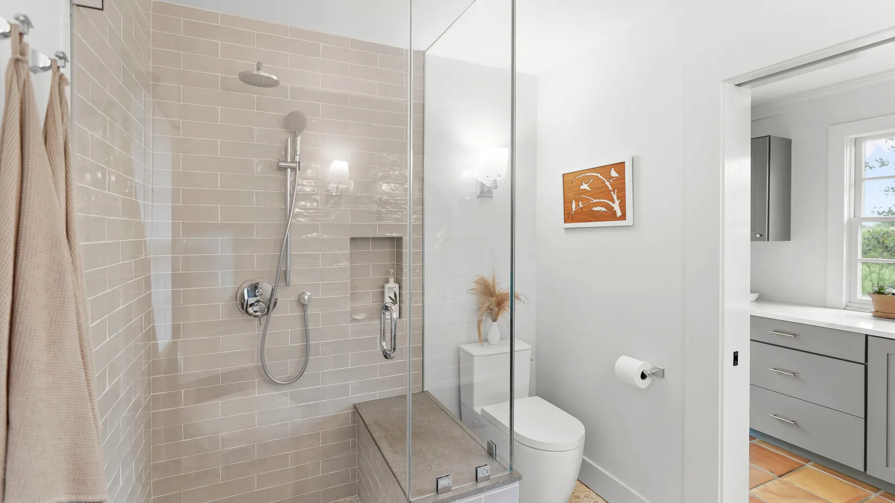 Un baño luminoso con ducha de vidrio, inodoro y lavabo.