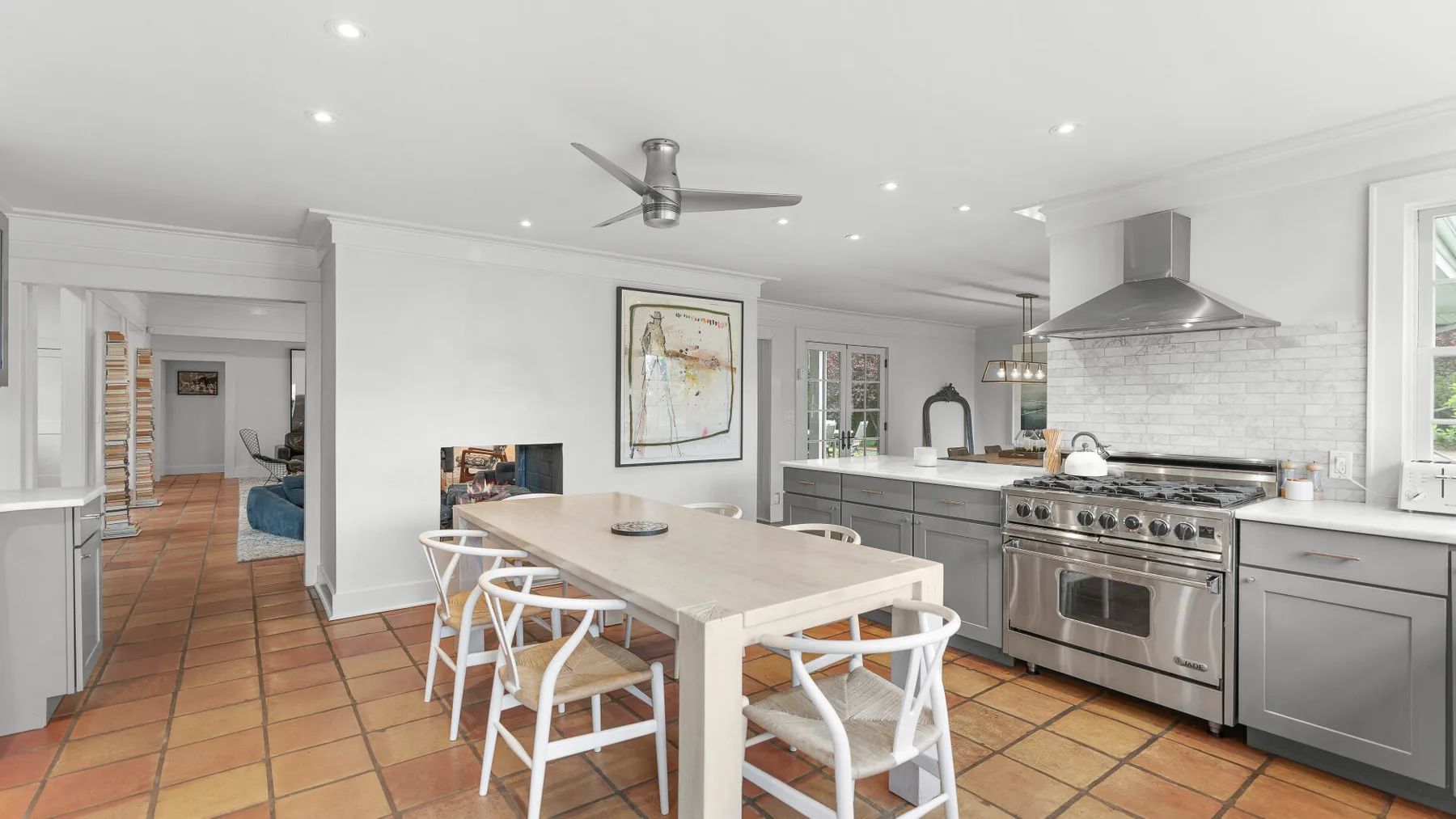 Una cocina luminosa con comedor, una mesa larga y una estufa de acero inoxidable.