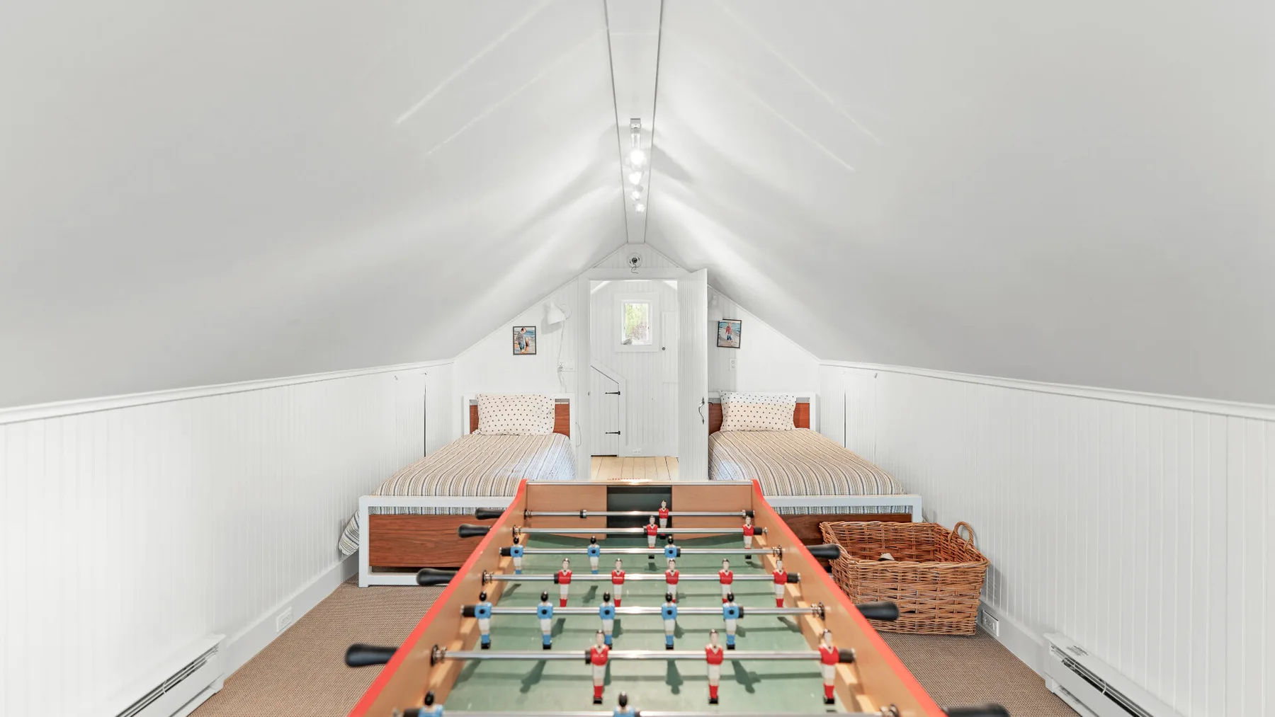 Un luminoso cuarto de juegos en el ático con futbolín y dos camas.