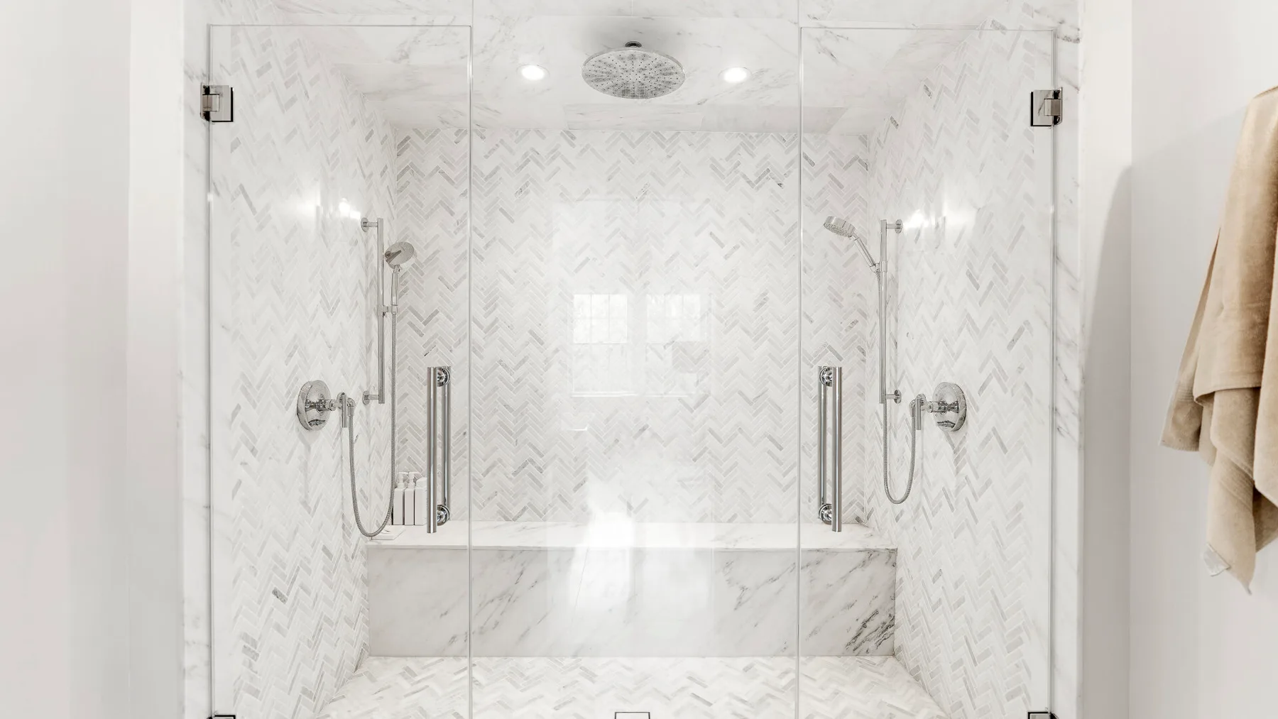 Una zona de ducha con azulejos, paneles de vidrio y accesorios de pared.