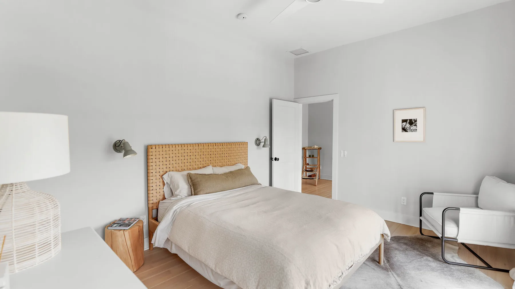 Un dormitorio luminoso con una cama, una mesita de noche y asientos junto a la pared.