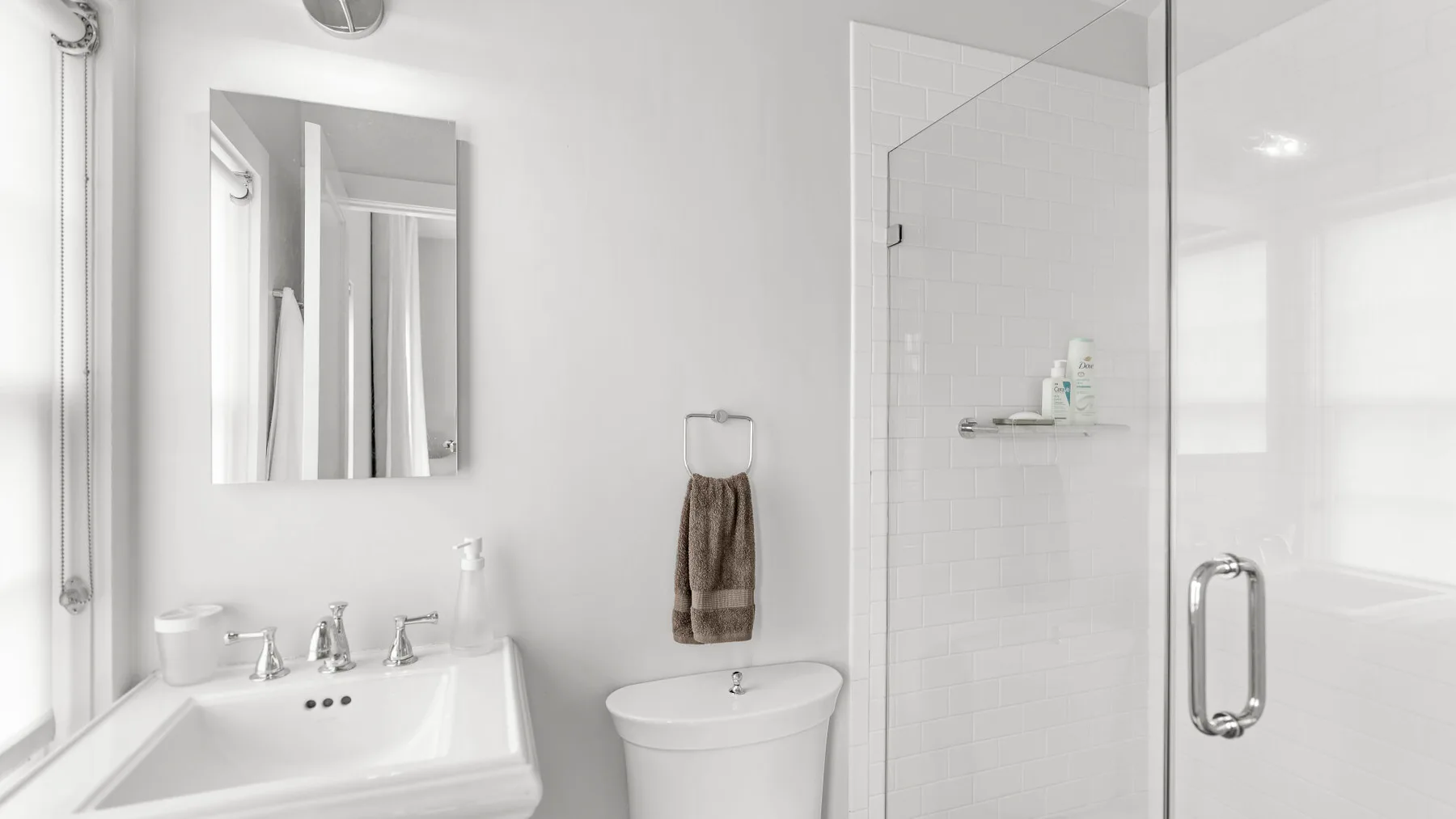 Un baño luminoso con lavabo, inodoro y ducha de vidrio.