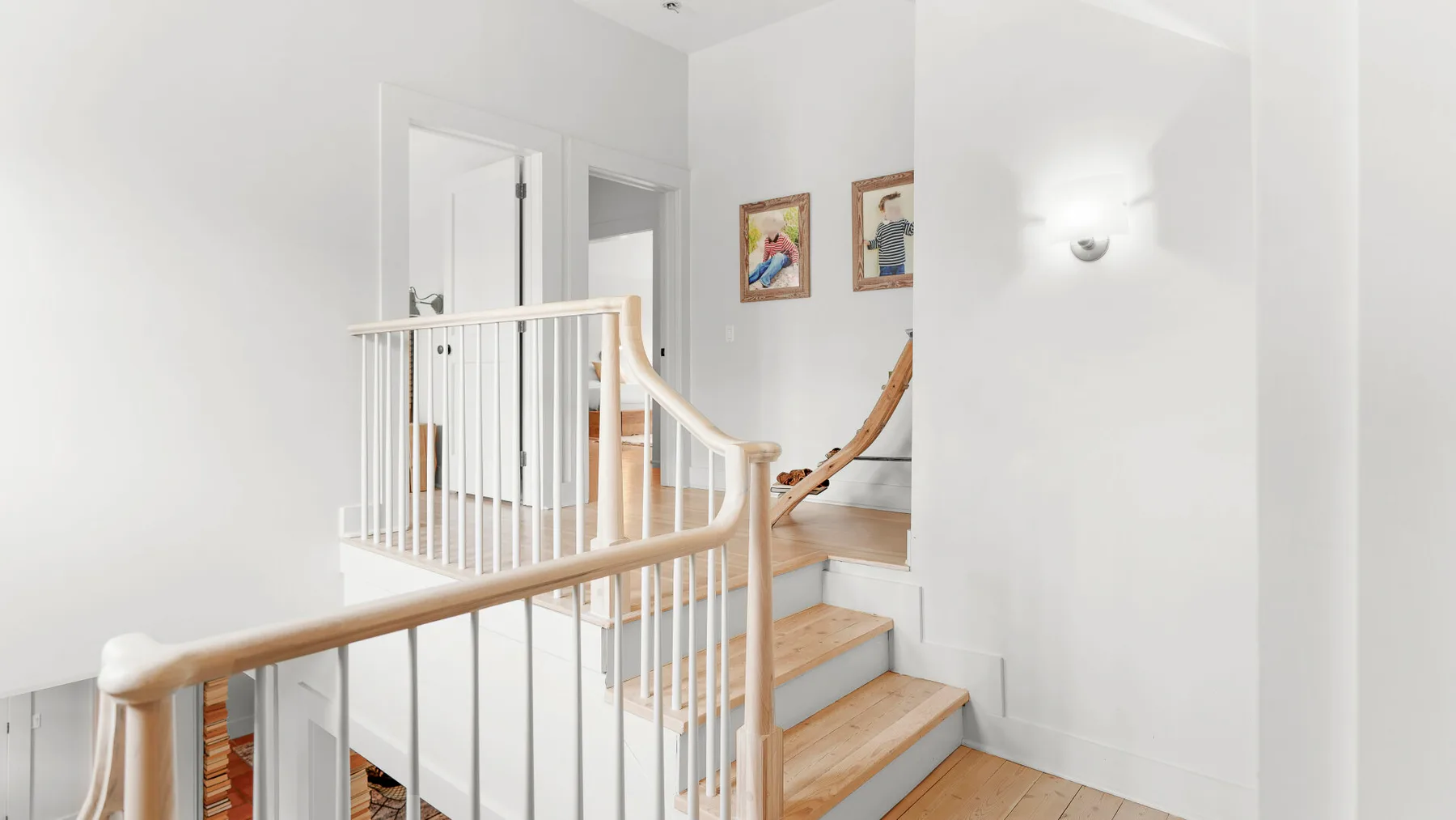 Una escalera luminosa con peldaños de madera y barandillas blancas.