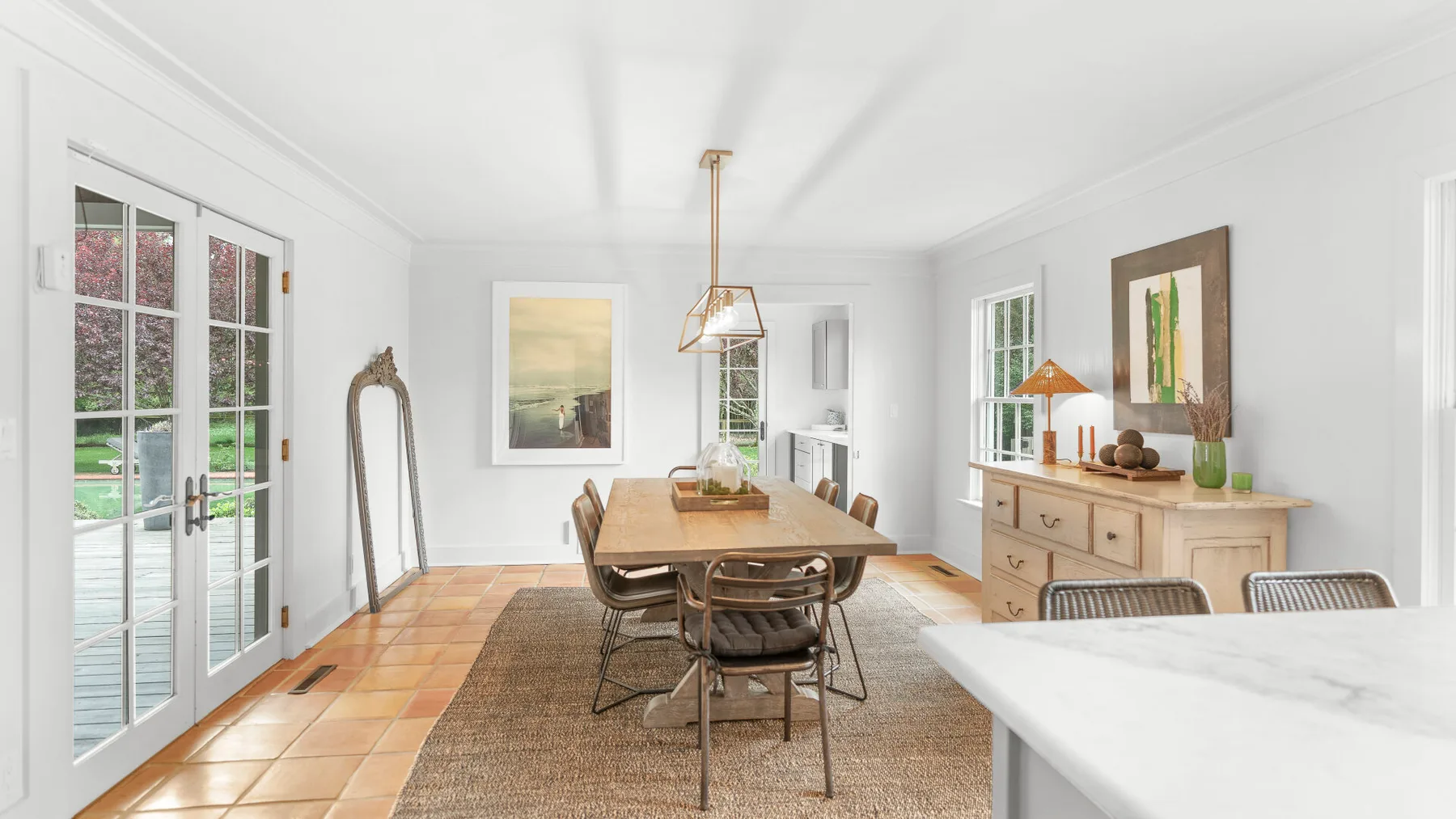 Un comedor luminoso con una mesa larga de madera y ventanas grandes.