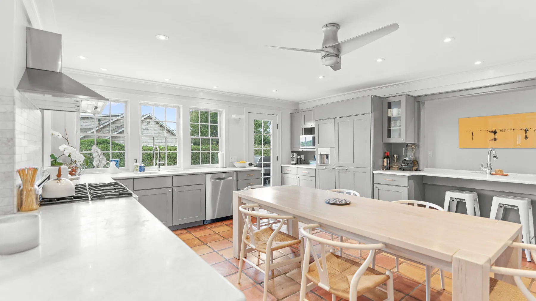Una cocina luminosa con una mesa de comedor larga y grandes ventanas.