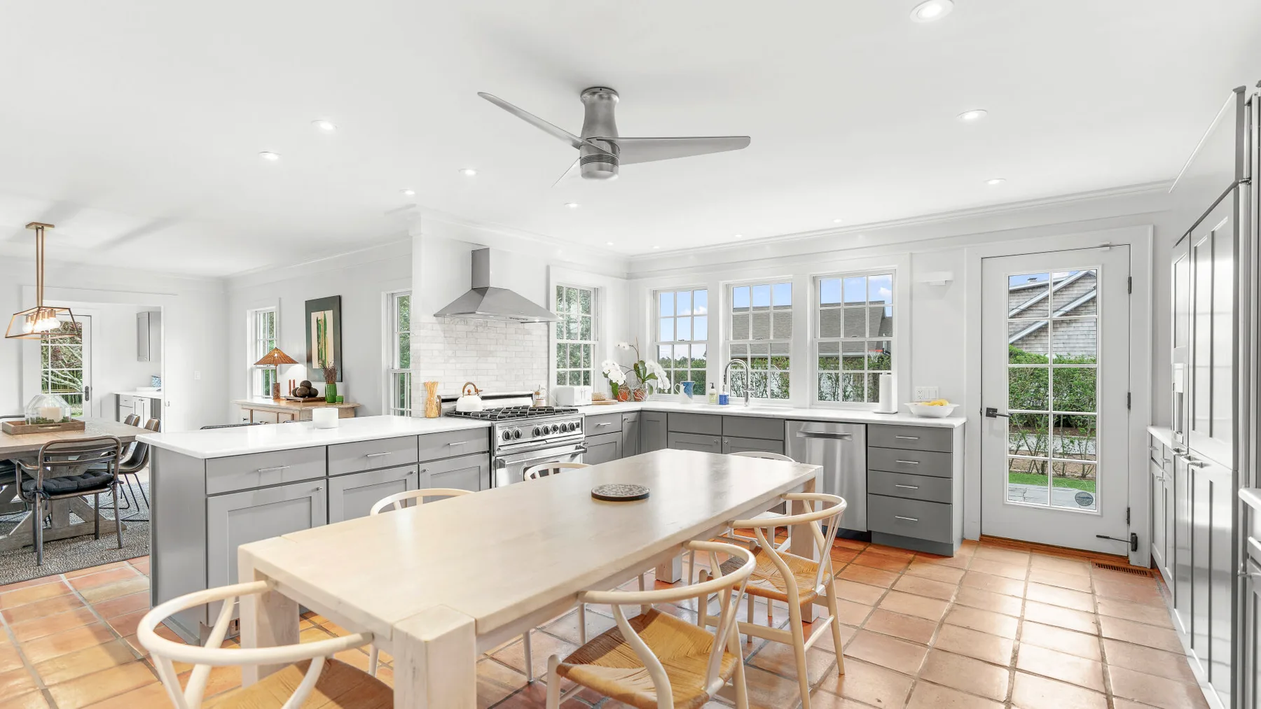 Una luminosa cocina y comedor con una mesa grande y ventanas.