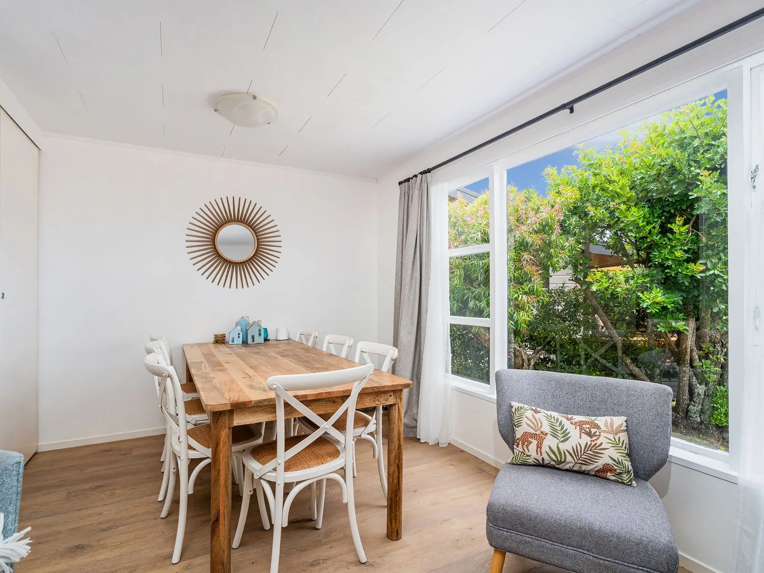 A dining table with chairs and a mirror in Slice of Pauanui - Pauanui
