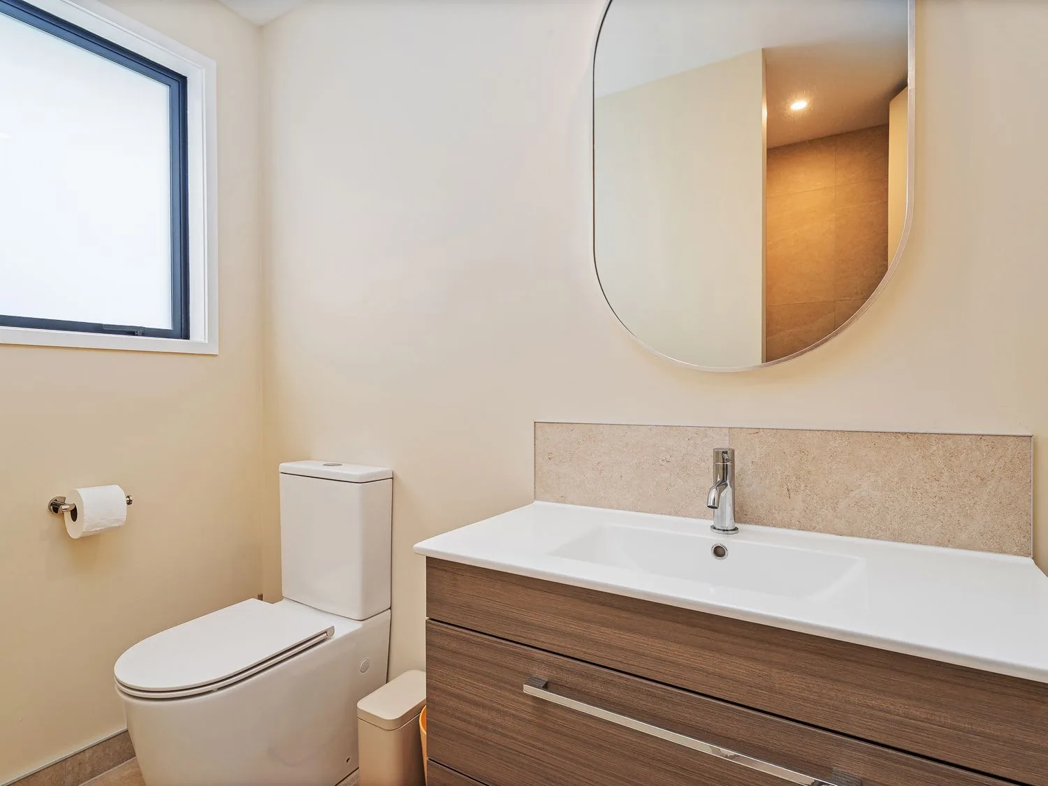A bathroom featuring a toilet and a sink with a mirror at Slice of Pauanui - Pauanui