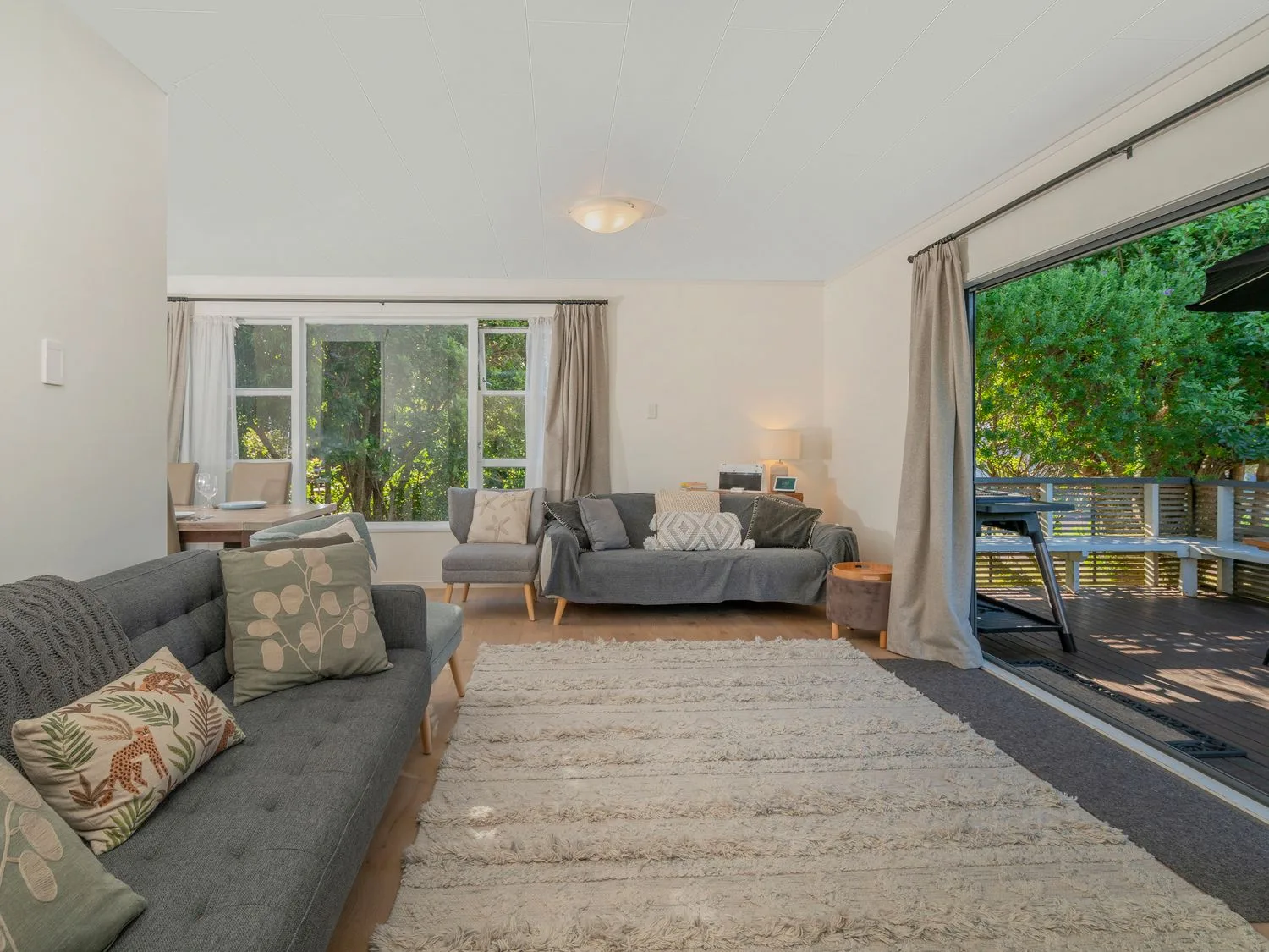 A living room with seating and a rug beside an open sliding door to a deck.