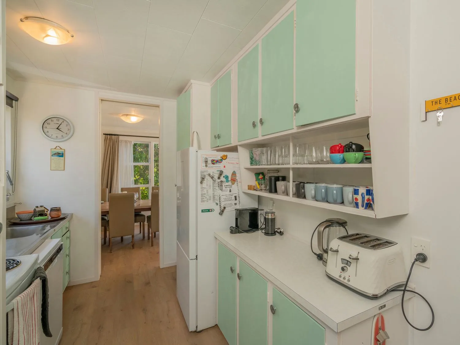 A kitchen with mint-green cabinets, a refrigerator, and countertop appliances.