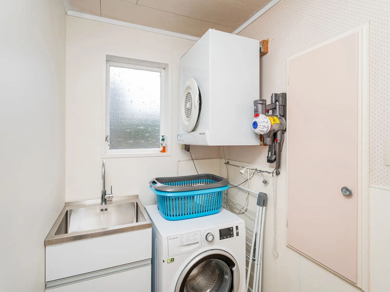 A laundry room with a washing machine, dryer, sink, and laundry basket at Slice of Pauanui - Pauanui