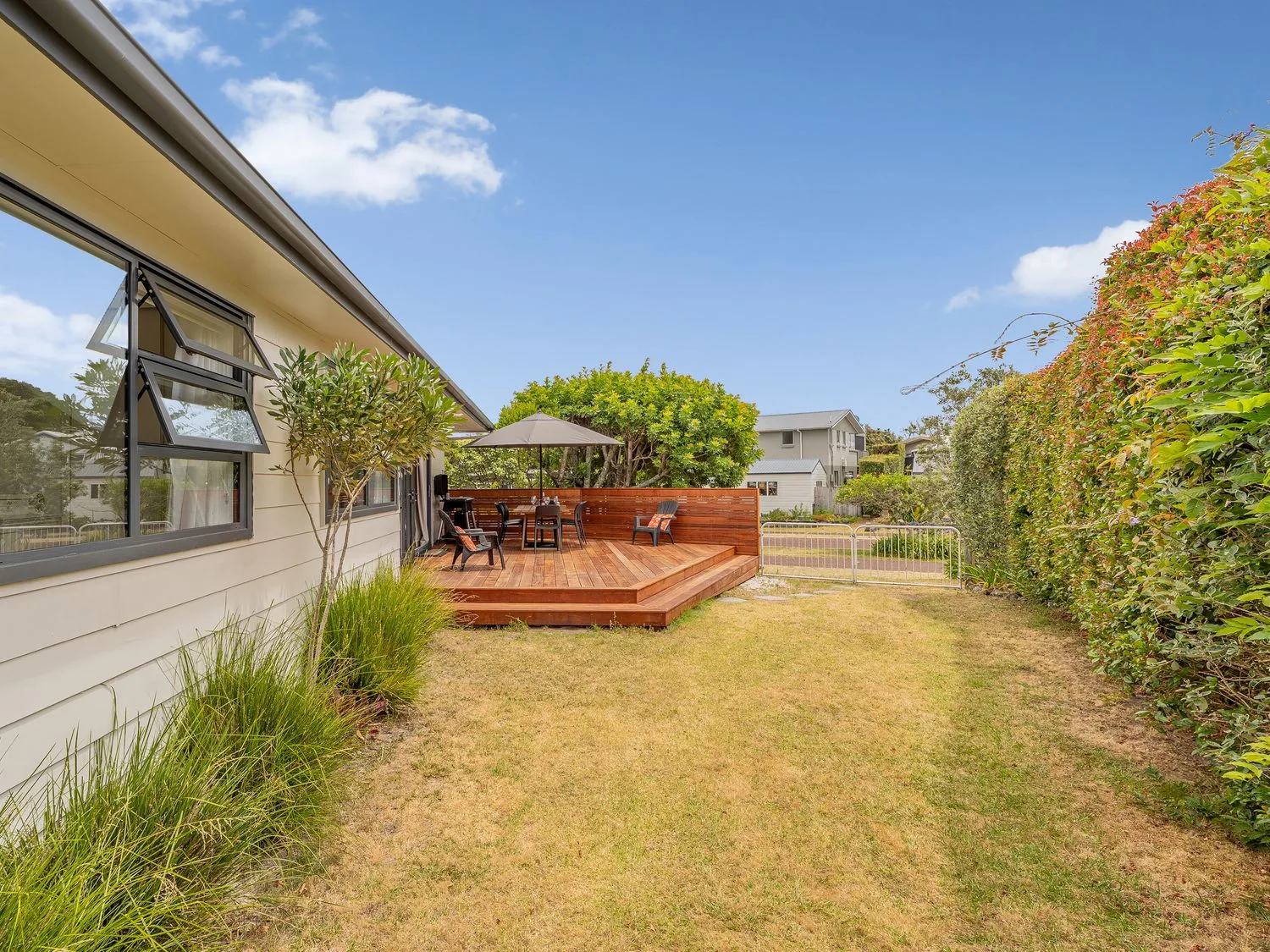A patio area with a deck, table and chairs at Slice of Pauanui - Pauanui Holiday Home, Pauanui