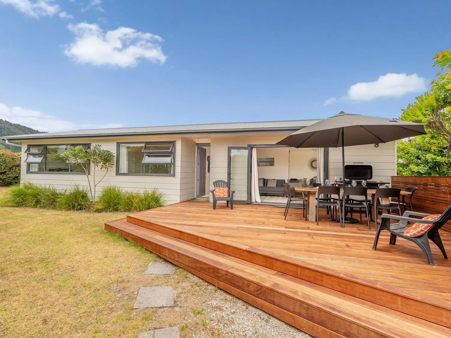 A house with a wooden deck and outdoor seating at Slice of Pauanui - Pauanui Holiday Home