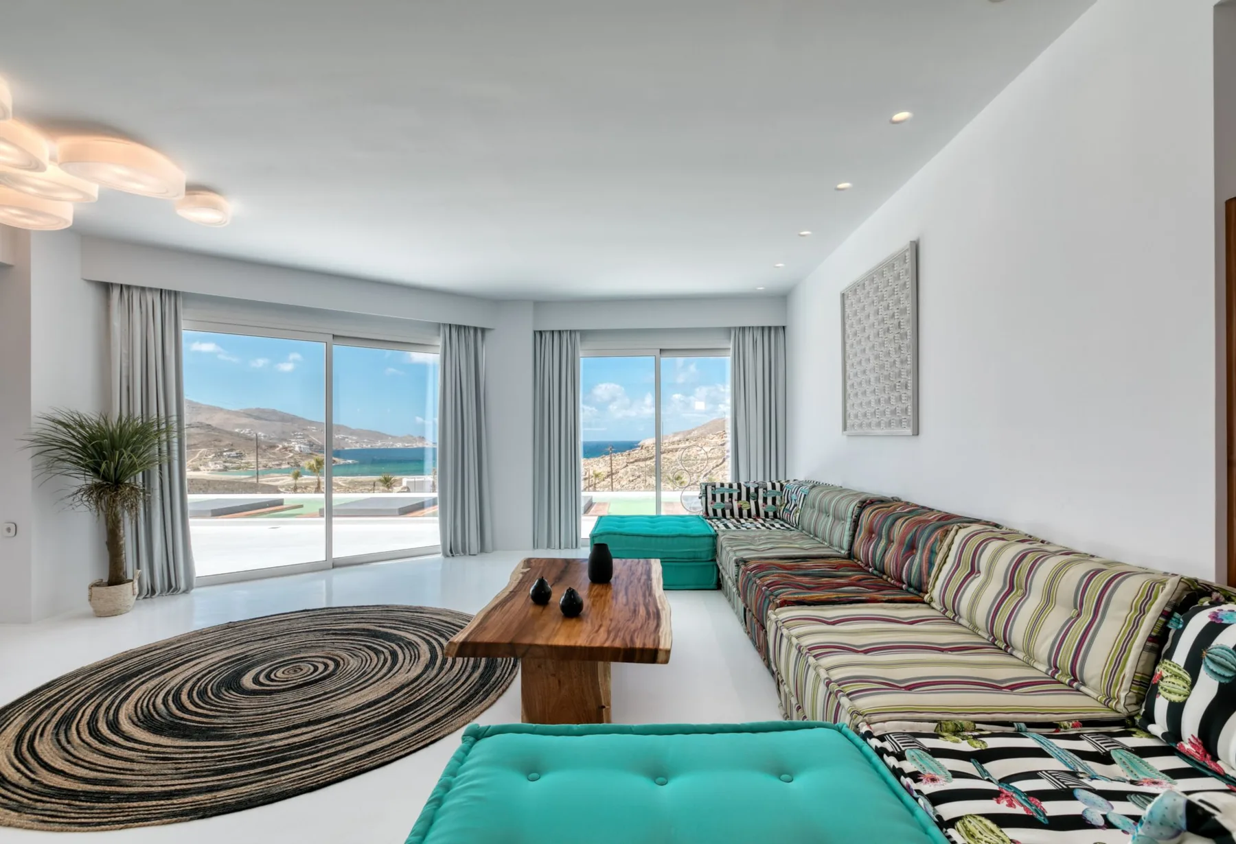 Bright living room with a long patterned sofa and wide windows overlooking the water.