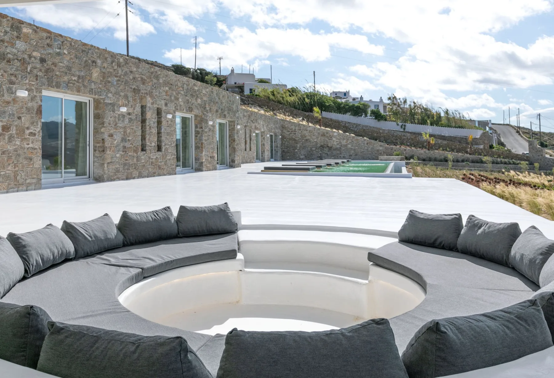 An outdoor patio with curved seating surrounding a recessed circular area.