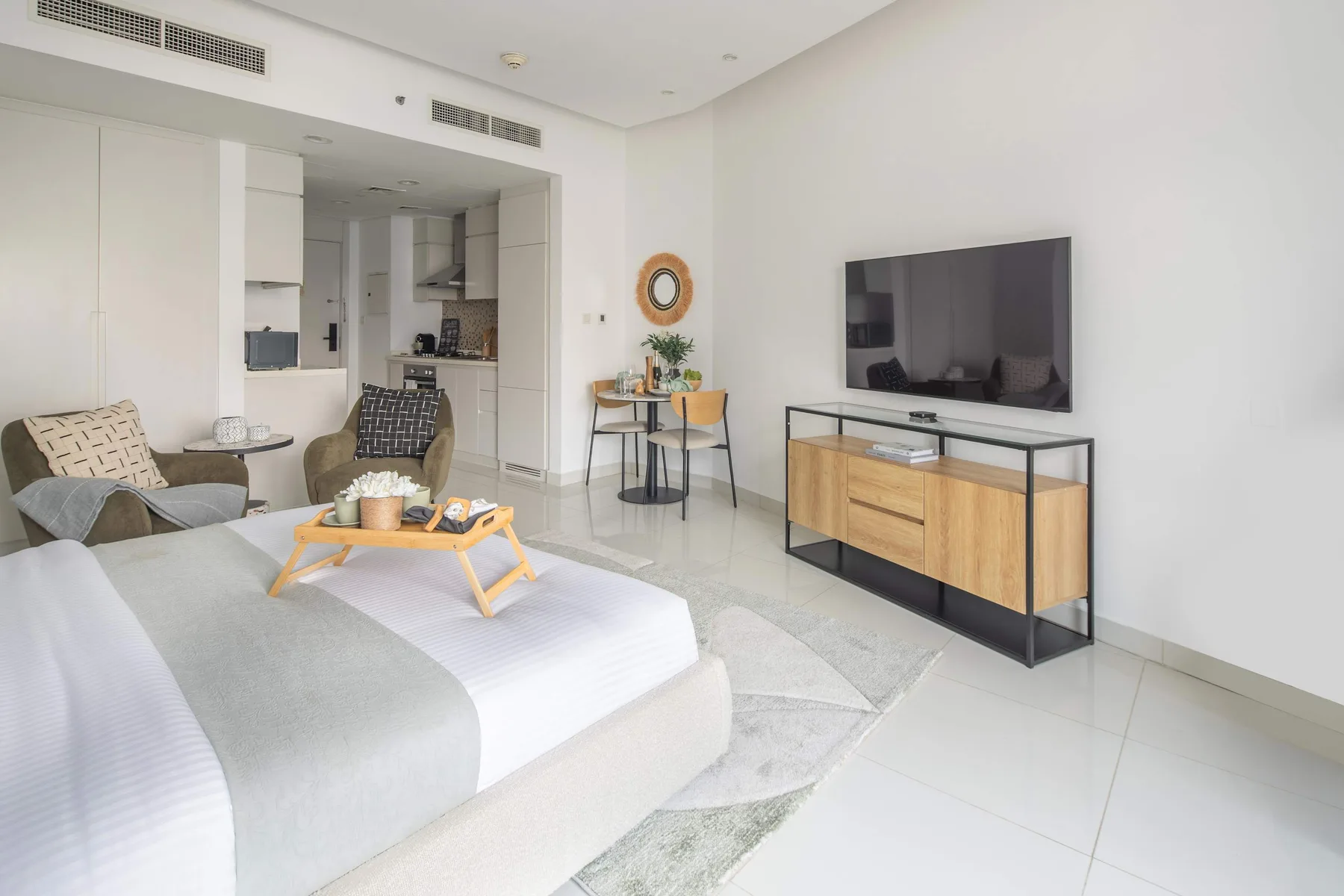 Un dormitorio luminoso con cama, zona de asientos y televisor.
