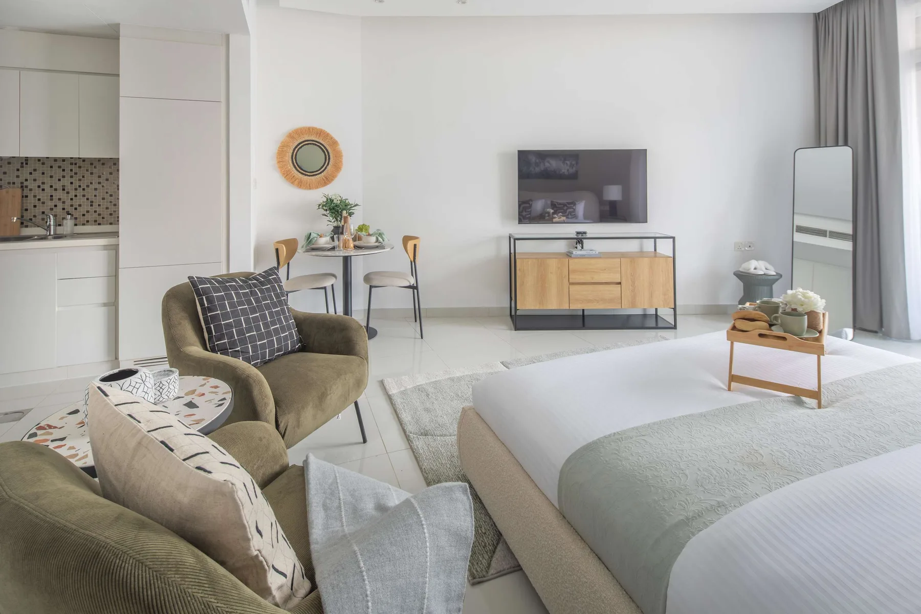 A bright living room with seating, a television, and a dining table.