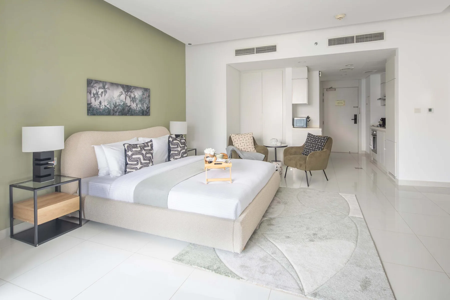 A bright bedroom with a bed, bedside table, and seating area.