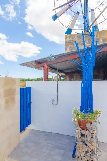 Una ducha al aire libre con estructuras pintadas de azul y suelo de baldosas.