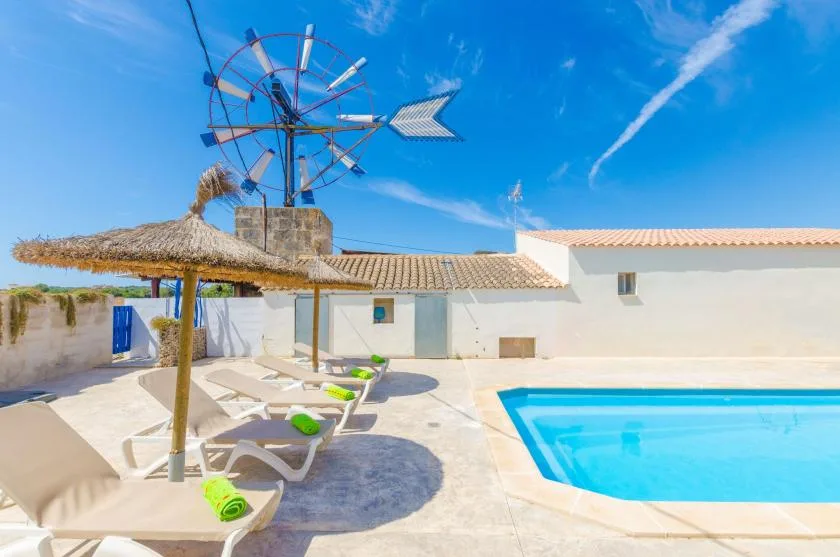 Una zona de piscina al aire libre con tumbonas y una sombrilla de paja.