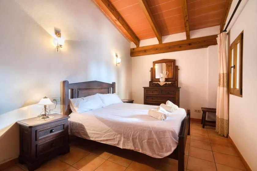 Un dormitorio con una cama, mesitas de noche y un techo con vigas de madera.