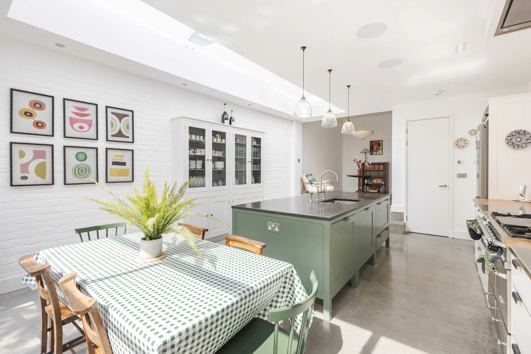 A bright kitchen with a central island and a dining table.